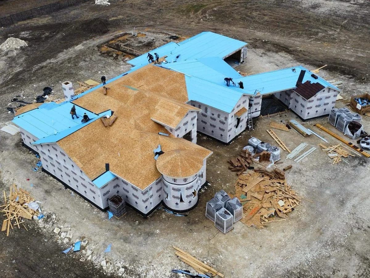 Professional roofing crew installing new shingles on Texas home with materials staged on roof