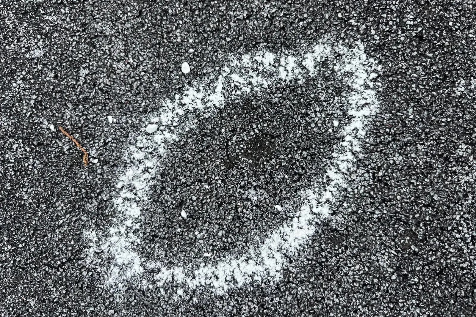 Chalk-circled hail impact mark on an asphalt shingle
