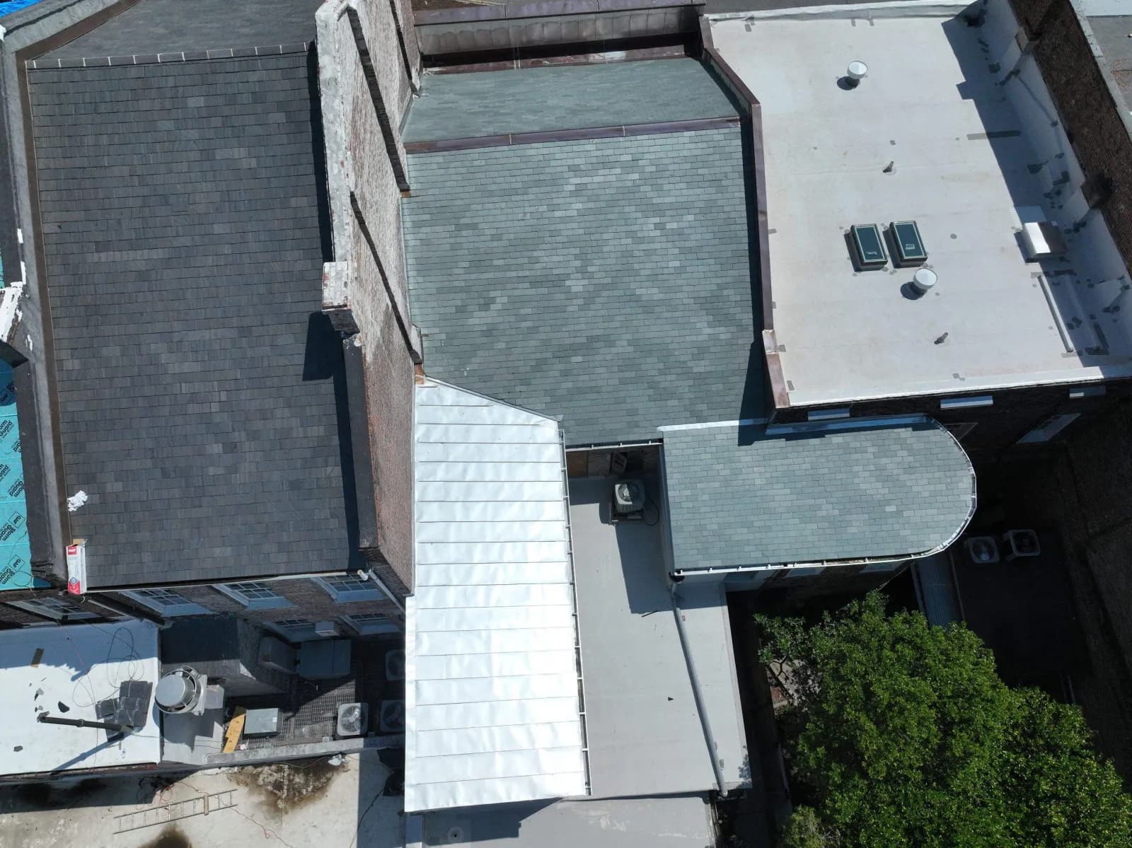 Side-by-side comparison of synthetic composite slate shingles and natural quarried slate tiles on a roof