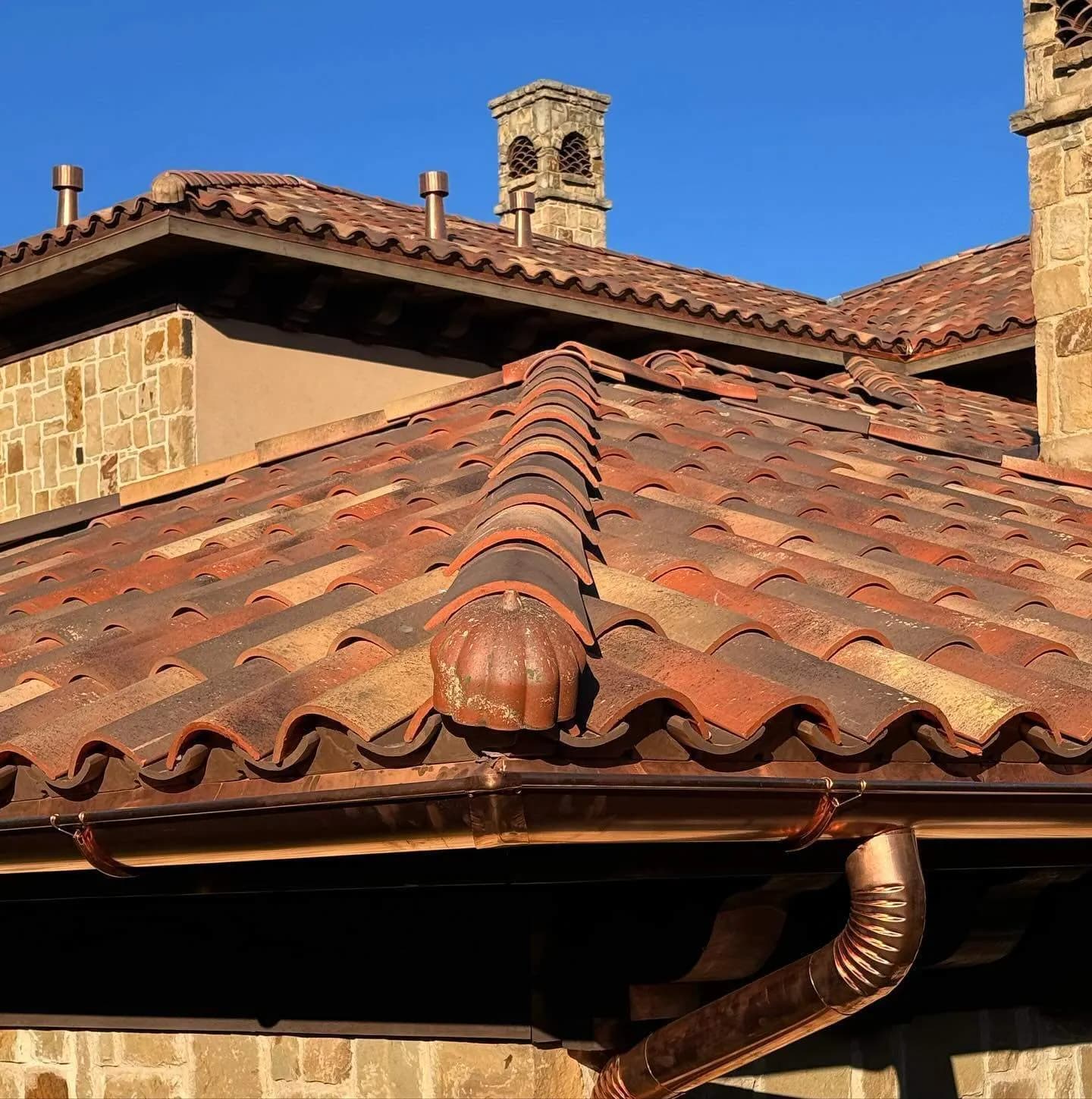 Finished copper gutter and downspout on a clay tile residence