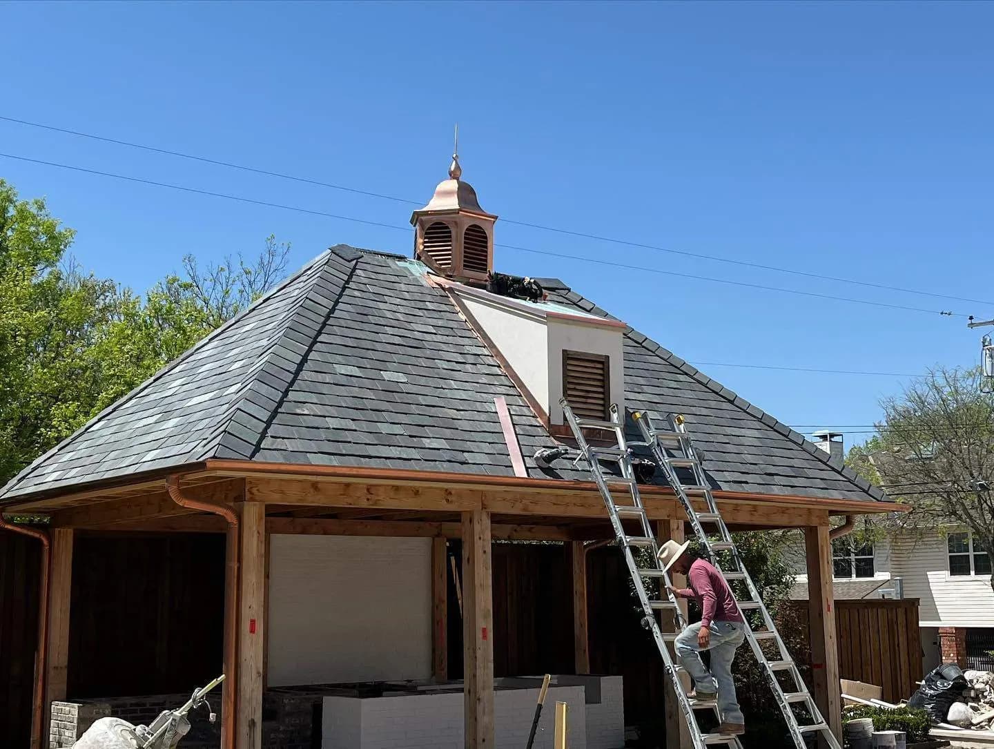 Craftsman finishing a copper cupola atop a slate roof