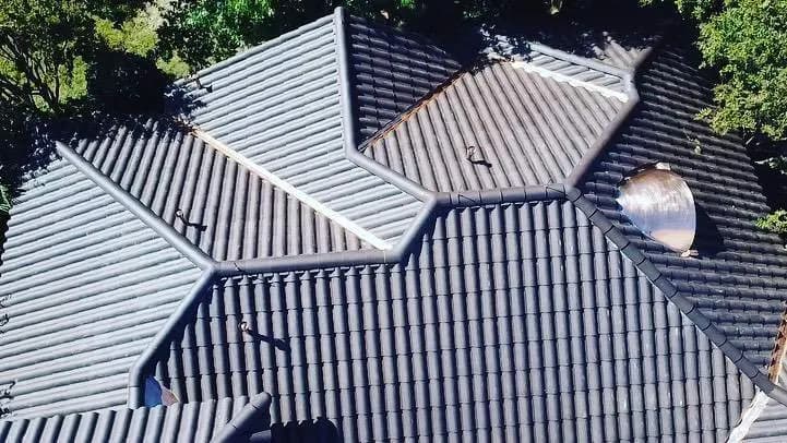 Aerial detail of a complex dark clay tile roof with intersecting hips and valleys