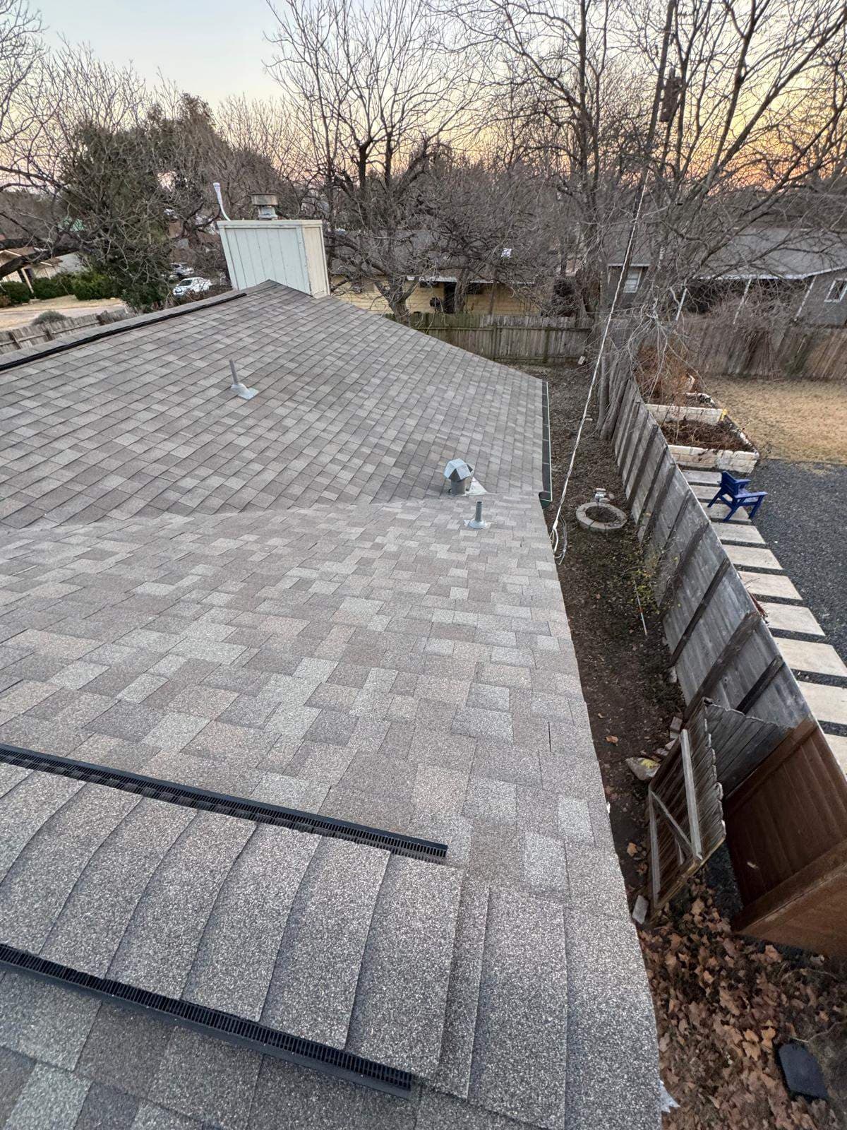 Austin shingle roof showing intake vent strips near the eaves, ridge ventilation, and metal flashing around roof penetrations