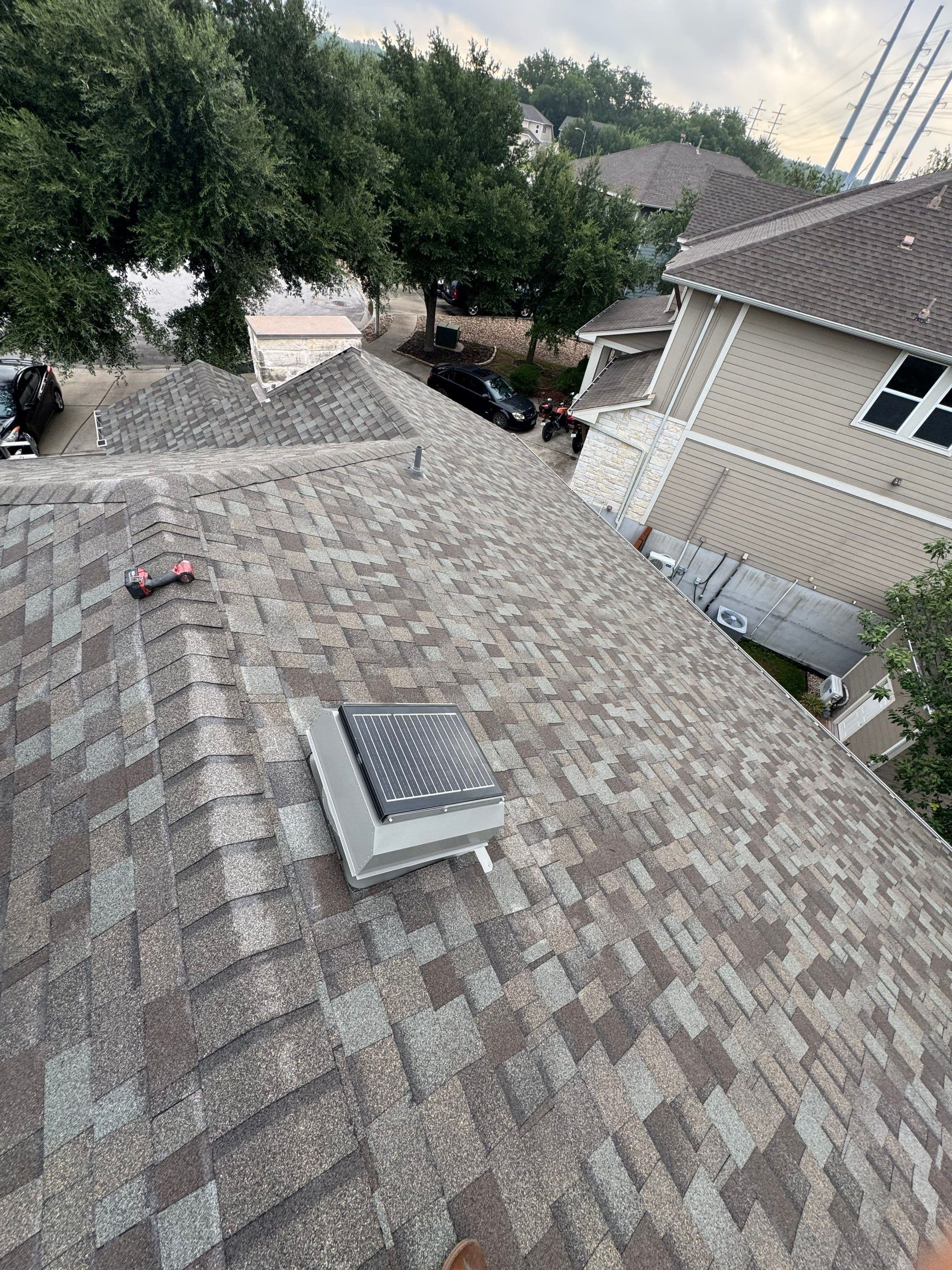 Shingles and an installed solar attic vent on an Austin roof, photographed in July 2026