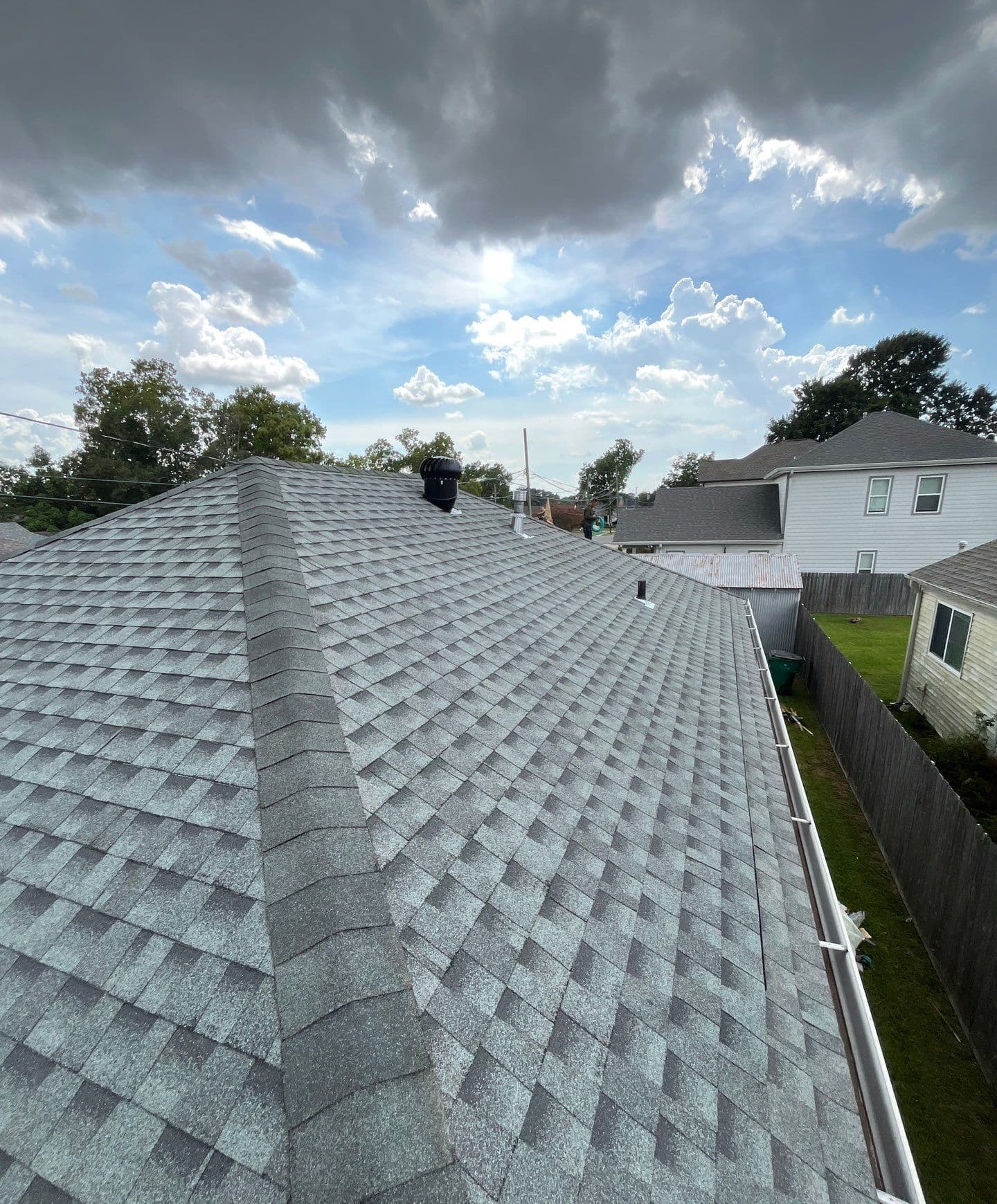 Gray architectural shingles along a capped hip with a turbine vent and gutter edge on a Metairie roof