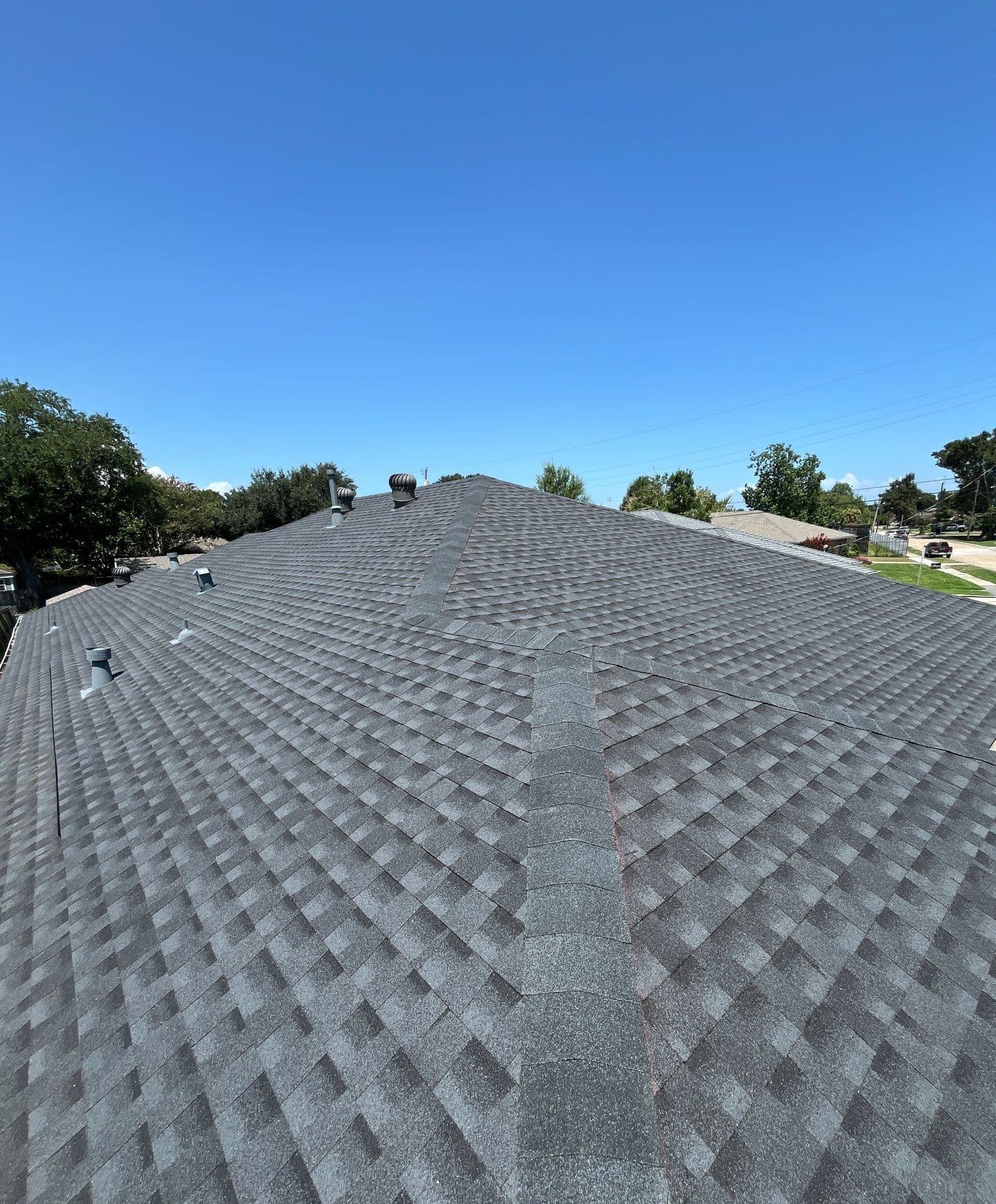 Installed architectural shingles and hip caps on a Metairie roof with turbine vents and roof penetrations visible