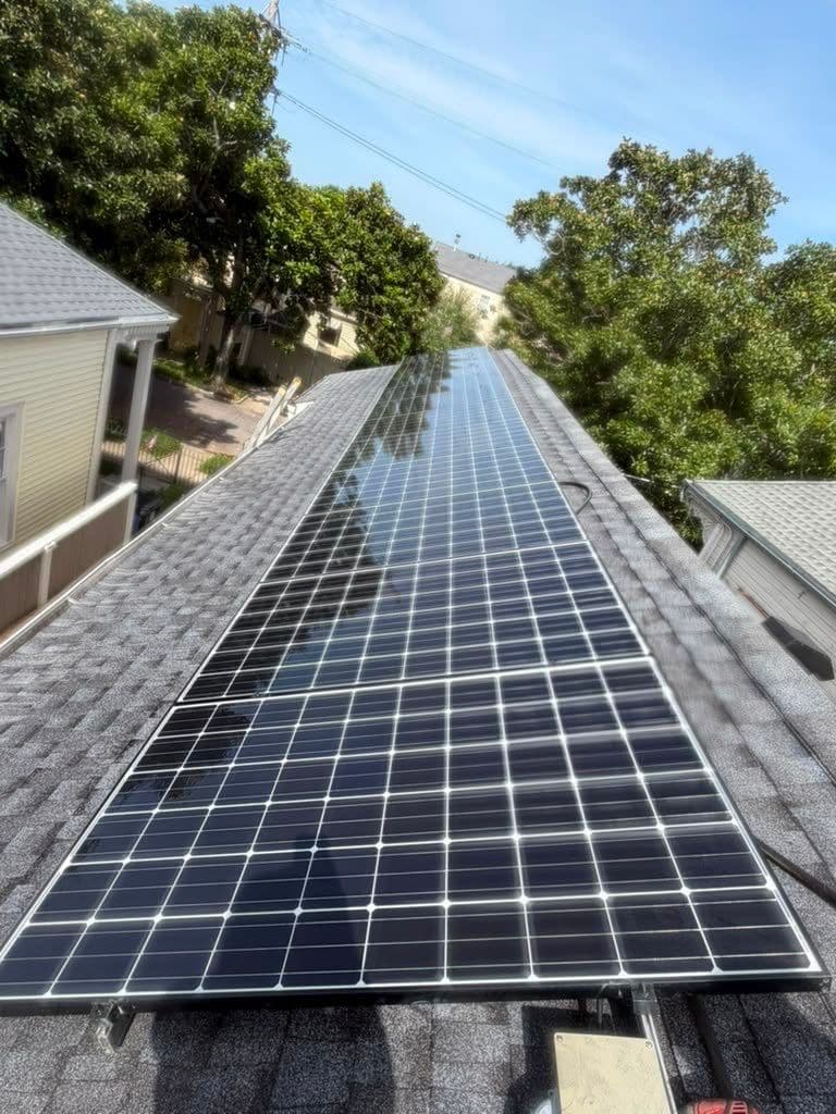Solar panels above installed shingles on a New Orleans roof in July 2026