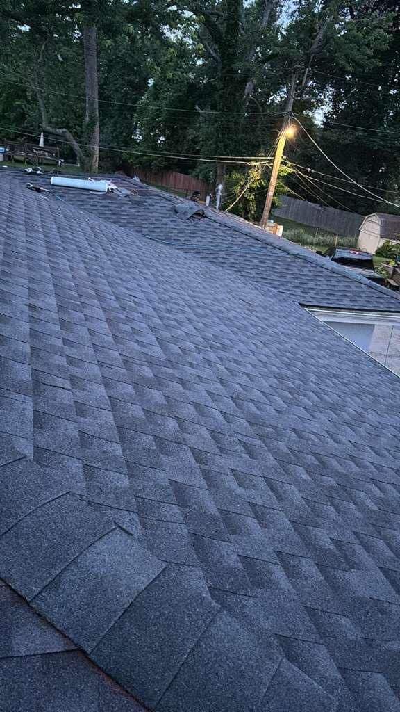 Installed gray shingles during a St. Louis roof project, with materials still visible toward the far end