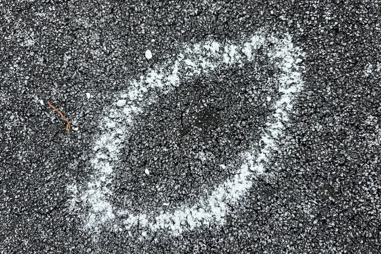 Chalk-circled hail impact mark on an asphalt shingle