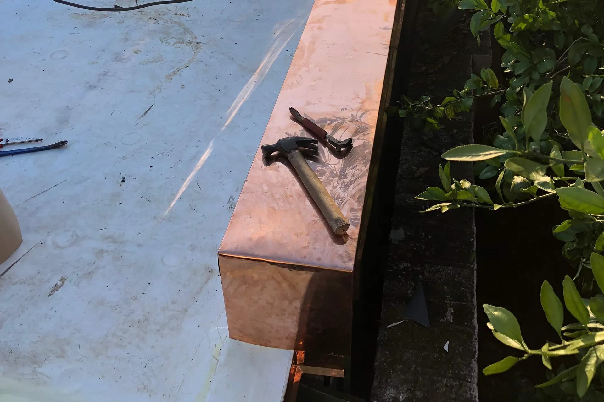 Copper parapet cap and hand tools during a roof repair on an Uptown New Orleans home