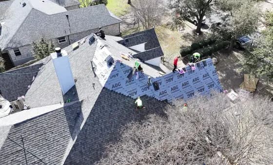 Roofing crew installing underlayment and shingles around roof penetrations