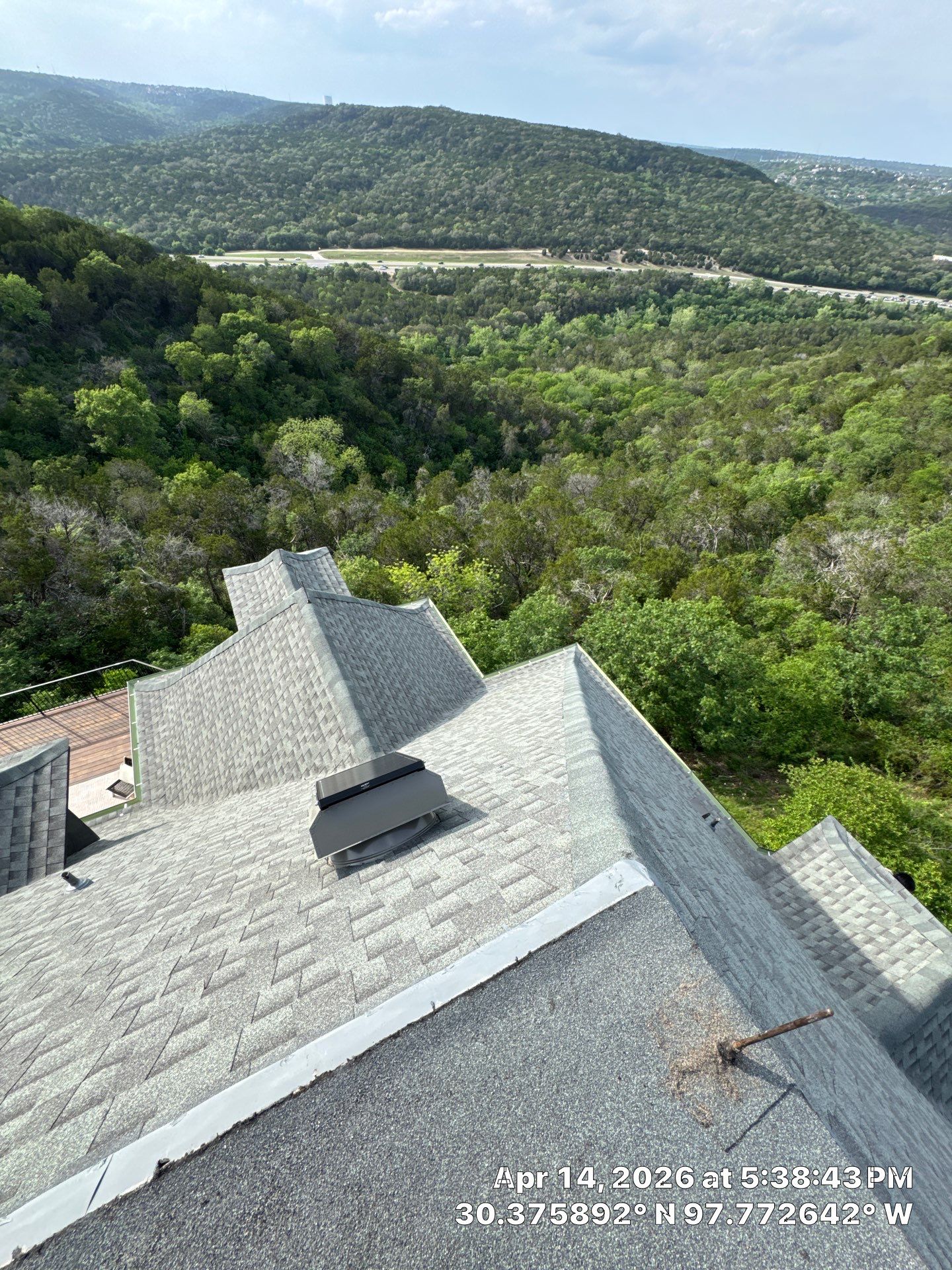 Connected shingle roof slopes and surrounding wooded hills at a Valburn Drive property in Austin