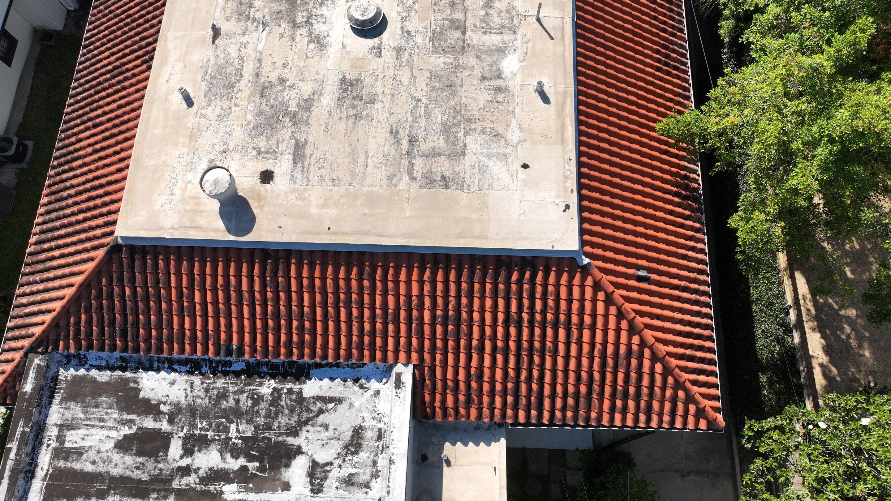 Pitched tile roofing meeting low-slope roof sections at a New Orleans property